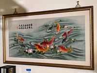 Frontal view of the large framed embroidery artwork showing eight colorful Japanese carp swimming in stylized water with lotus flowers and Chinese/Japanese characters in the top left corner.