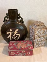 Photo showing all three items: large flat round vase, square lidded box, and square covered jar grouped together.