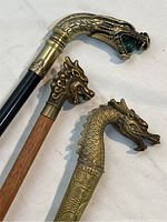 Close-up of three brass dragon head handles showing different designs