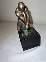 Front angle view of bronze statuette showing seated figure and black base