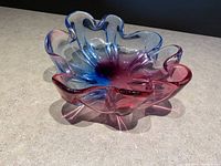 Angle showing ruffled edges and gradient coloring from blue to cranberry red on a handmade glass bowl.