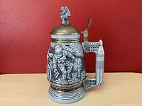 Front and side views of the Avon Conquest of Space stein showing detailed astronaut and space scene artwork with pewter lid and decorative finial.