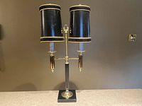 Front view of the French Bouillotte tri-light lamp showing dual black tole shades with gold trim, black and brass metal stem, and square base.