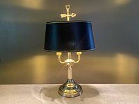Front view of the bronze bouillotte lamp with black shade and arrow finial, showing overall design and proportions.