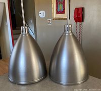 Pair of conical industrial pendant light shades by DVI Lighting, showing brushed metal finish.