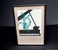 Full view of framed Jan Roy serigraph poster. Artwork depicts a cat silhouette on a grand piano with a fern plant on top. Beige background with text crediting artist and printer.