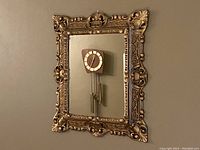 Front view of the ornate vintage Italian wall mirror with gold frame and decorative accents.