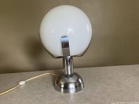 Photo of the lamp with the white glass globe shade on, showing the full lamp in off state.