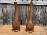 Pair of wooden genie bottle lamps on wooden table against outdoor wooden fence background