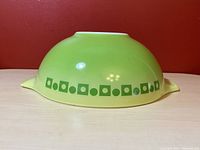 Side view of the Pyrex bowl showing green dot square pattern and small handle spout
