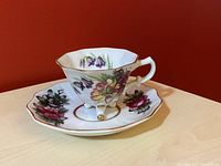 Image of vintage footed mini teacup with floral pattern sitting on matching saucer
