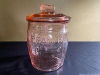 Front and side view of the pink glass jar showing embossed PEANUTS text and barrel shape