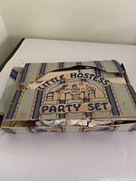 Original packaging box for the Little Hostess Party Set, showing wear and tear, designed with blue stripes and cartoon illustration
