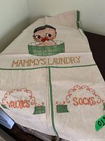 Full view of vintage laundry bag laying flat showing printed graphic of person in tub and "Mammy's Laundry" text.