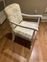 Side view of the occasional chair showing upholstery and wooden armrest and legs