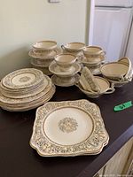 Full view of stacked luncheon plates, soup bowls with plates, tea cups with saucers, and serving plates on a table.