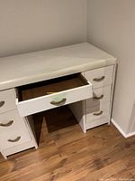Front view of small white desk with an open central drawer showing wooden interior and smooth drawer operation.