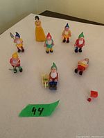 Full view of all nine plastic vintage Snow White and seven dwarfs cake toppers arranged on a surface.