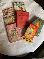 Top view of the six books arranged on a round white surface, showing all covers including the Jingle Jangle Nursery Rhyme Book, Charlotte's Web, Three Little Pigs, Noah's Ark, Aesop's Fables, Small Tyke's Club Stories.