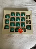 Boxed set of 18 vintage glass Christmas ball ornaments, 15 blue and 3 silver visible.