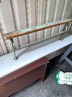 Photo of the full vintage paper roll cutter affixed to a wooden board, showing its length, metal blade, and legs.