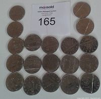 Photo showing 19 Canadian dollar coins in used condition, arranged in rows. Includes coins dated between 1969 and 1985, mostly featuring Voyageur and Bluenose designs.