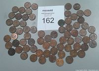 Photo showing assortment of 71 Canadian one-cent coins spread in a rough circle with a label indicating lot number 162.