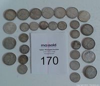 Top-down view of all coins arranged around auction lot card number 170. Coins are silver-colored with mixed wear and tarnish.