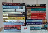 Photo of 23 hardcover Danielle Steel books stacked and lined in 3 columns showing colored spines and titles, some with dust jackets, various colors and publication years.
