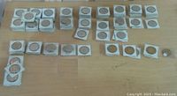 Overview of all coins laid out on a table in 2x2 holders and loose: assorted coins from Kitchener Waterloo Octoberfest and some Fergus trade dollars.
