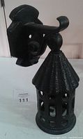 Side view of the black painted heavy cast iron outdoor light fixture showing mounting bracket and vented lantern shaped light housing.