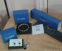 Full lot of three jewelry pieces with original blue boxes on a wooden surface: necklace, bracelet, earrings