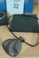 Photo showing the necklace with a multi-segment natural pattern pendant on a black cord.