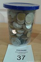 Plastic tub filled with a mix of various used world coins and tokens, no USA or Canada, weighing approximately 1.738kg