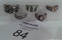 Five rings displayed on white foam, showing different designs with wear and marks