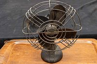 Front view of electrohome fan showing black metal blades enclosed in a circular metal cage with visible Electrohome Long Life badge on center.