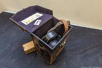 Leather carrying case opened with strap and a small unopened box next to it