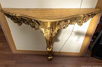 Front view of the 1950’s Florentine floating wall shelf showing carved gold-leaf detailing and wooden top surface.