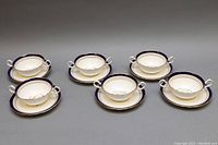 Six Aynsley Eskdale double-handle cream soup bowls with matching saucers arranged showing top and side views