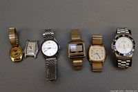 Full view of all six watches in the lot, showing variety of sizes, shapes, and metal tones, including gold and silver bracelets and bands.
