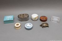 View of the eight assorted vintage trinket boxes displayed in a line on a white surface.