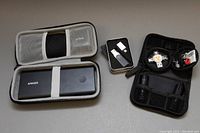 Overview of the lot showing Anker power bank in gray case on left, and multiple USB drives and accessories in two smaller cases on right.