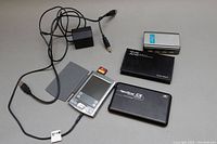 Overview photo showing Palm Pilot, multiple external hard drive cases, power adapter, and SD card cable