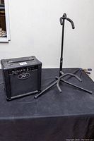 Peavey Backstage II amplifier and Profile guitar stand side by side on a black cloth surface.