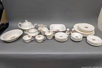 Full set laid out on grey background showing all items including teapot, serving bowls, dinner plates, luncheon plates, dessert plates, dessert bowls, teacups, saucers, salt and pepper shakers, sugar bowl and creamer.