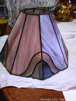 Full view of octagonal Tiffany style lamp shade showing purple and lilac stained glass panels with scalloped bottom edges and textured accent glass.