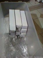 Plastic storage container with 15 white boxes lined up containing individual parrot bottle openers, sealed in plastic.