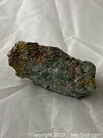 View of mineral chunk showing green zoisite with red ruby inclusions on rough surface.