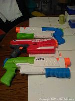 Three water soakers: white and blue, red and black MEGA, white and green, showing full set together