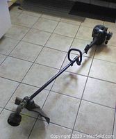 Full view of the Yardworks gas weedeater showing the engine, long shaft, handle, cutting head, and guard.